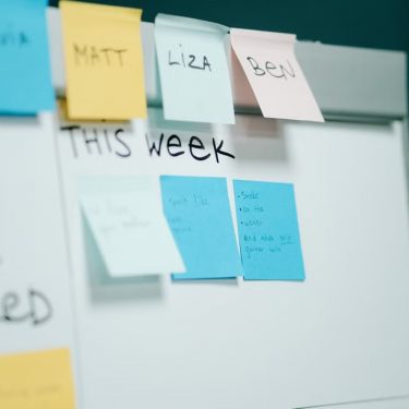 Close-up of a whiteboard with colorful sticky notes for task organization and planning.